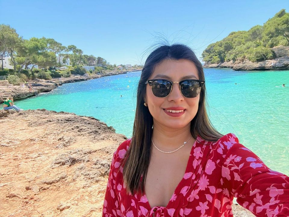 Woman in sunglasses smiling by the sea, the kind of face you meet on video chat with strangers